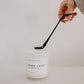 Candle with a black lid held by a hand on a light background