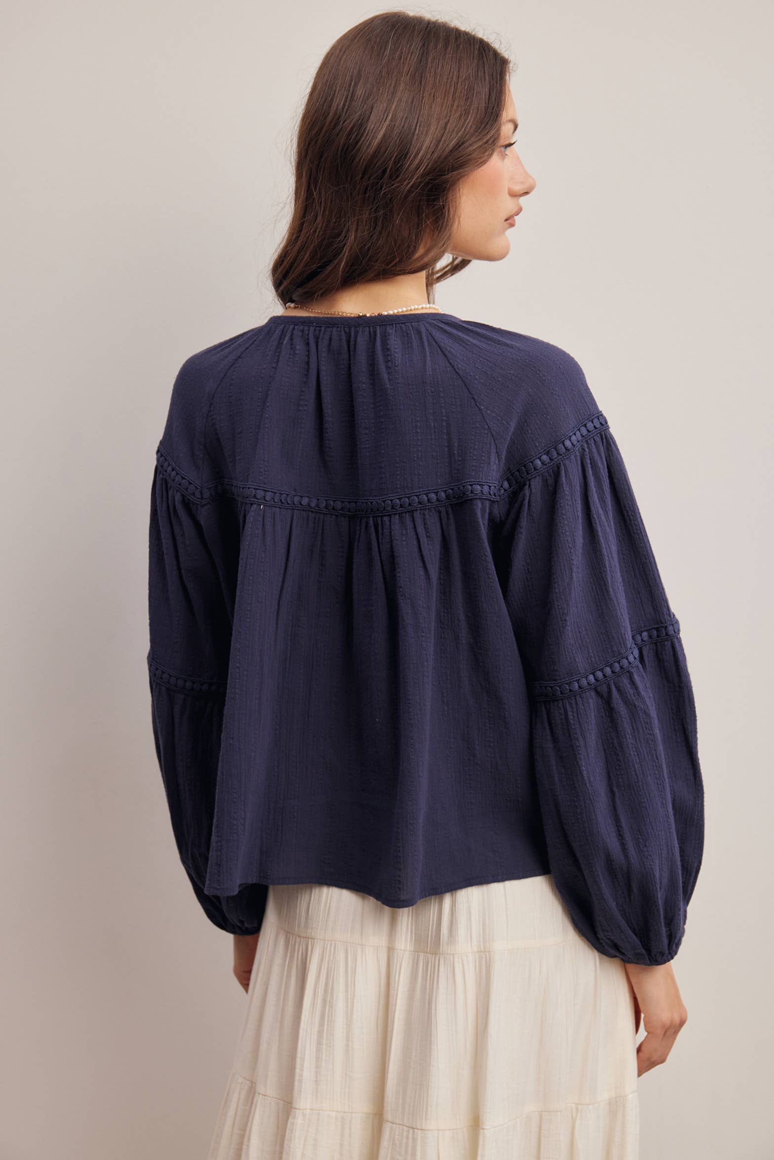 Woman wearing a navy blue blouse with long sleeves against a plain background