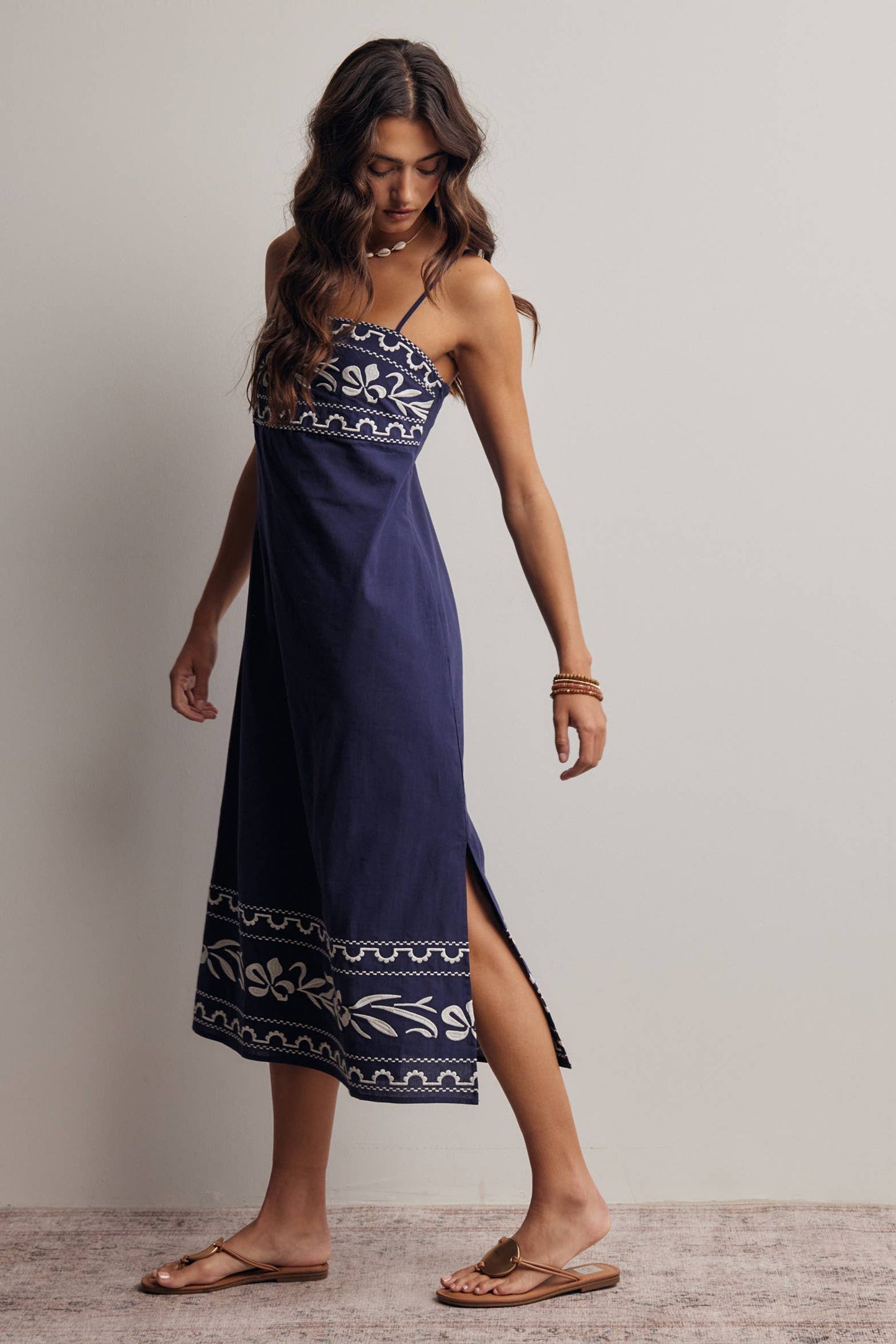 Woman wearing a navy blue dress with white patterns on a plain background