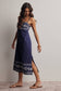 Woman wearing a navy blue dress with white patterns on a plain background