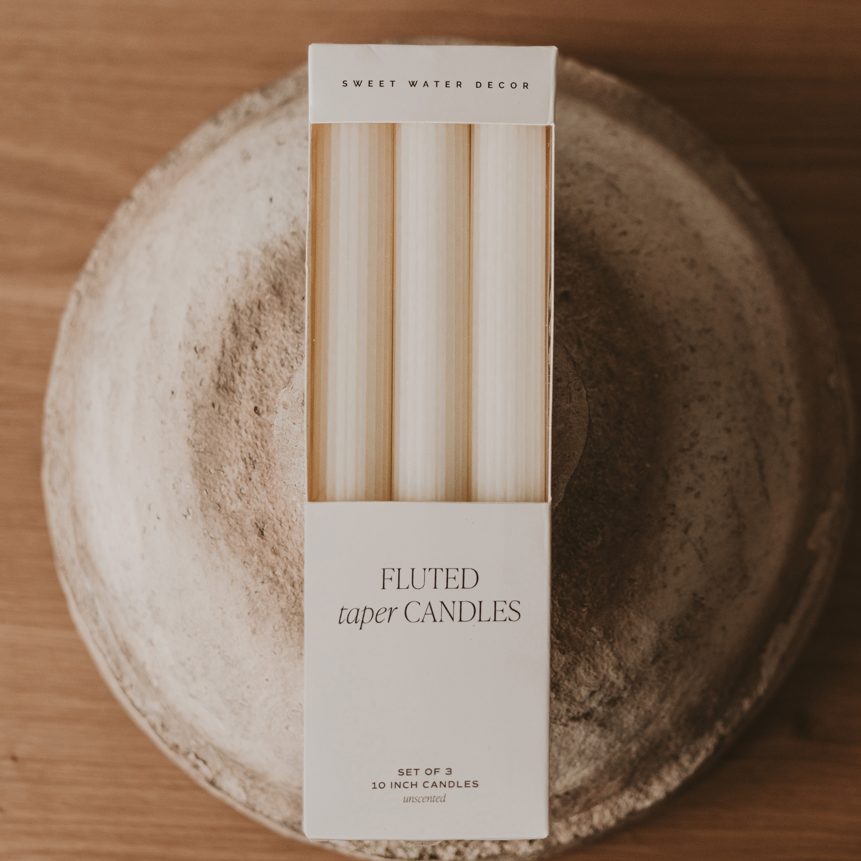 Box of fluted taper candles on a textured surface