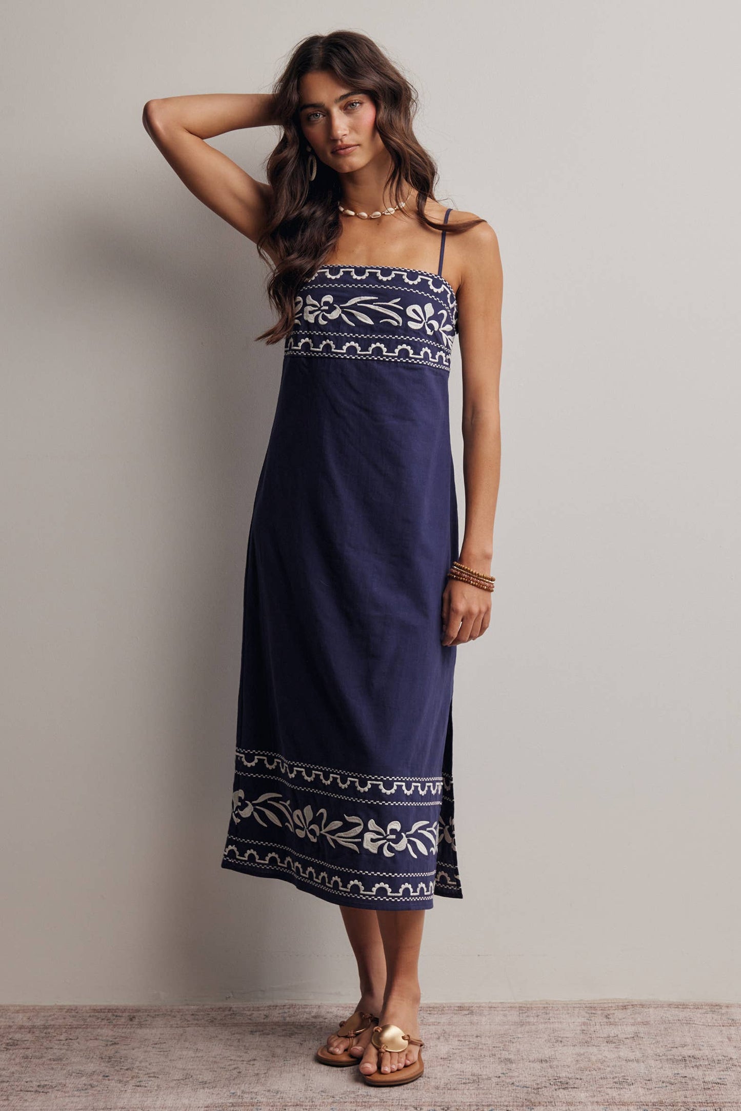 Woman wearing a navy blue dress with white patterns against a plain background