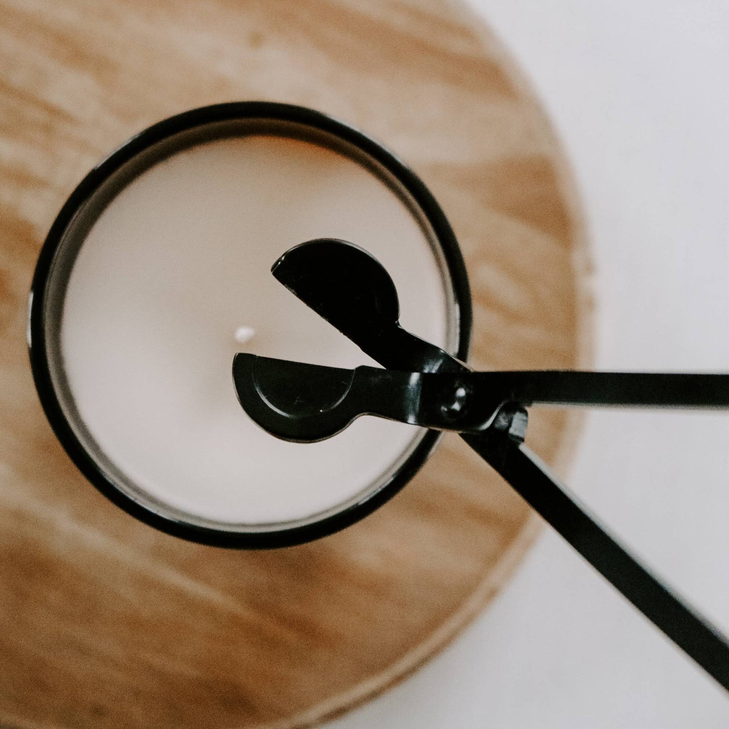 Close-up of a spoon stirring a cup of coffee on a wooden coaster.
