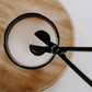 Close-up of a spoon stirring a cup of coffee on a wooden coaster.
