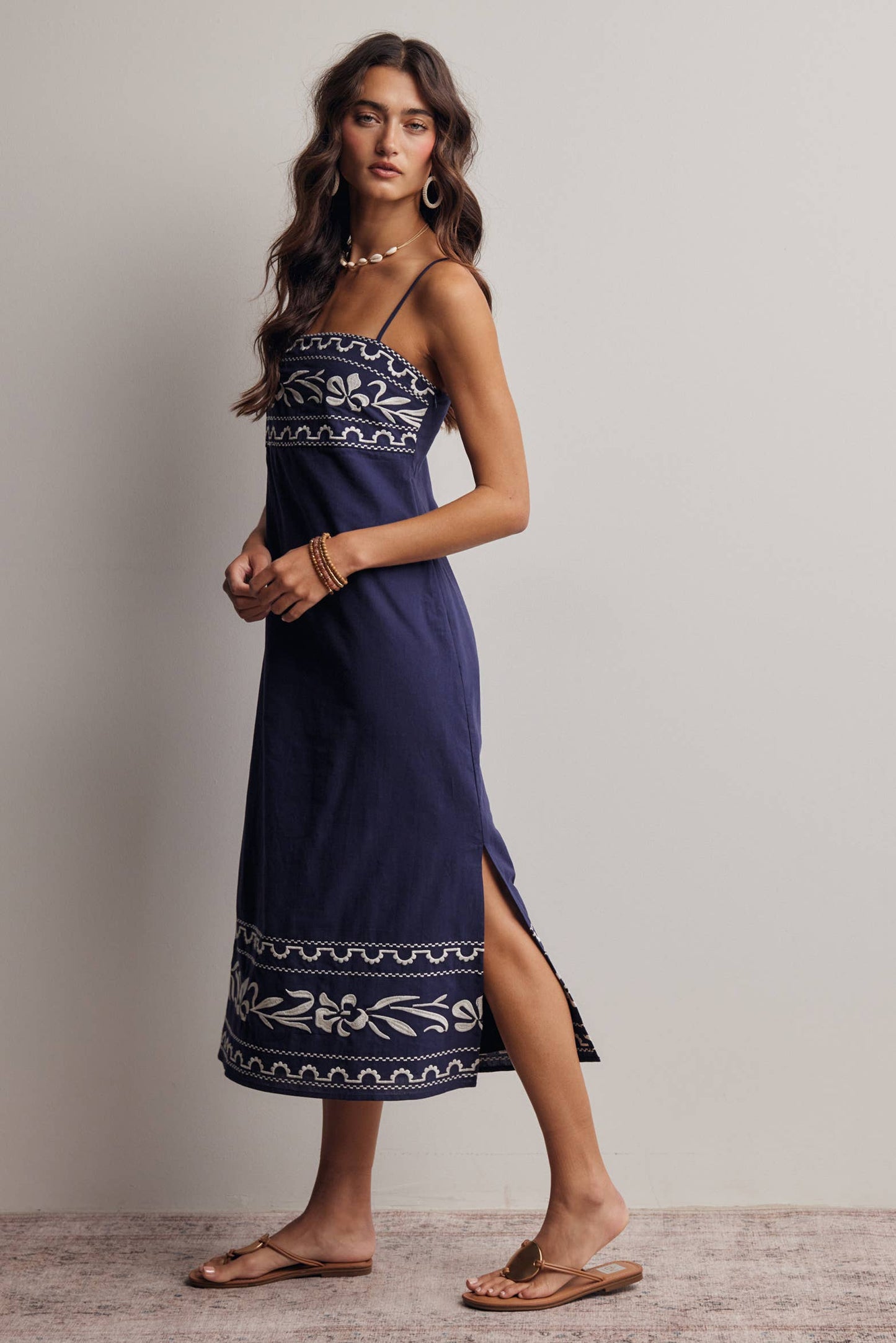Woman wearing a navy blue dress with white patterns on a plain background