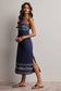 Woman wearing a navy blue dress with white patterns on a plain background