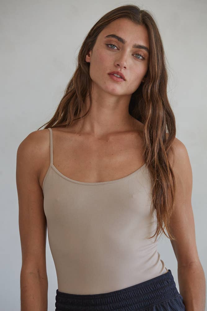 Woman wearing a beige tank top against a plain background