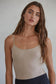 Woman wearing a beige tank top against a plain background