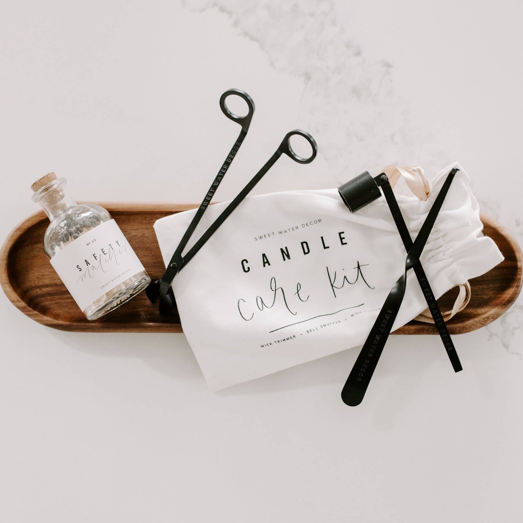 Matte black candle care kit with wick trimmer, candle snuffer, wick dipper, and drawstring storage pouch.