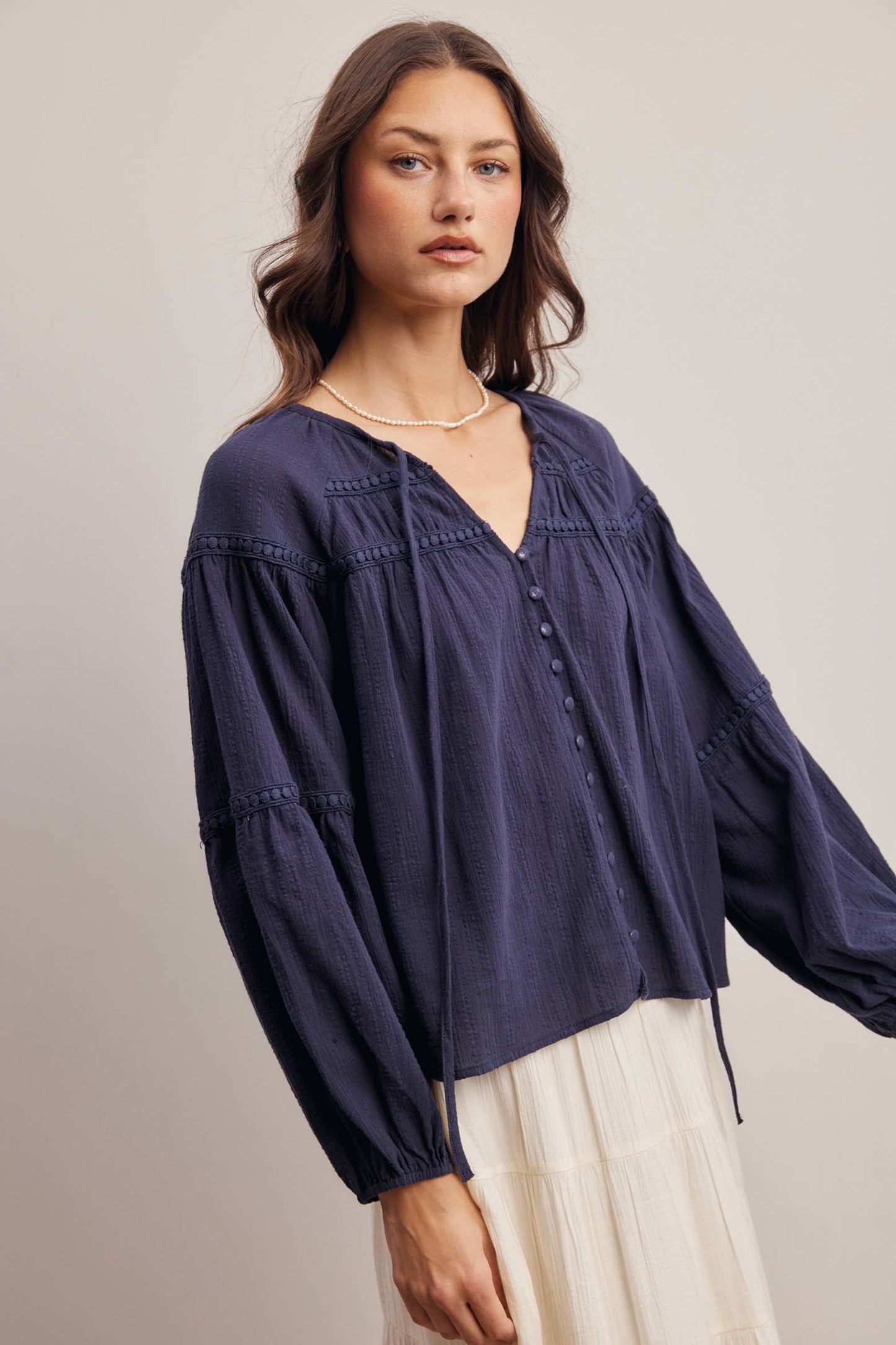Woman wearing a navy blue blouse with long sleeves on a plain background