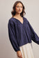 Woman wearing a navy blue blouse with long sleeves on a plain background