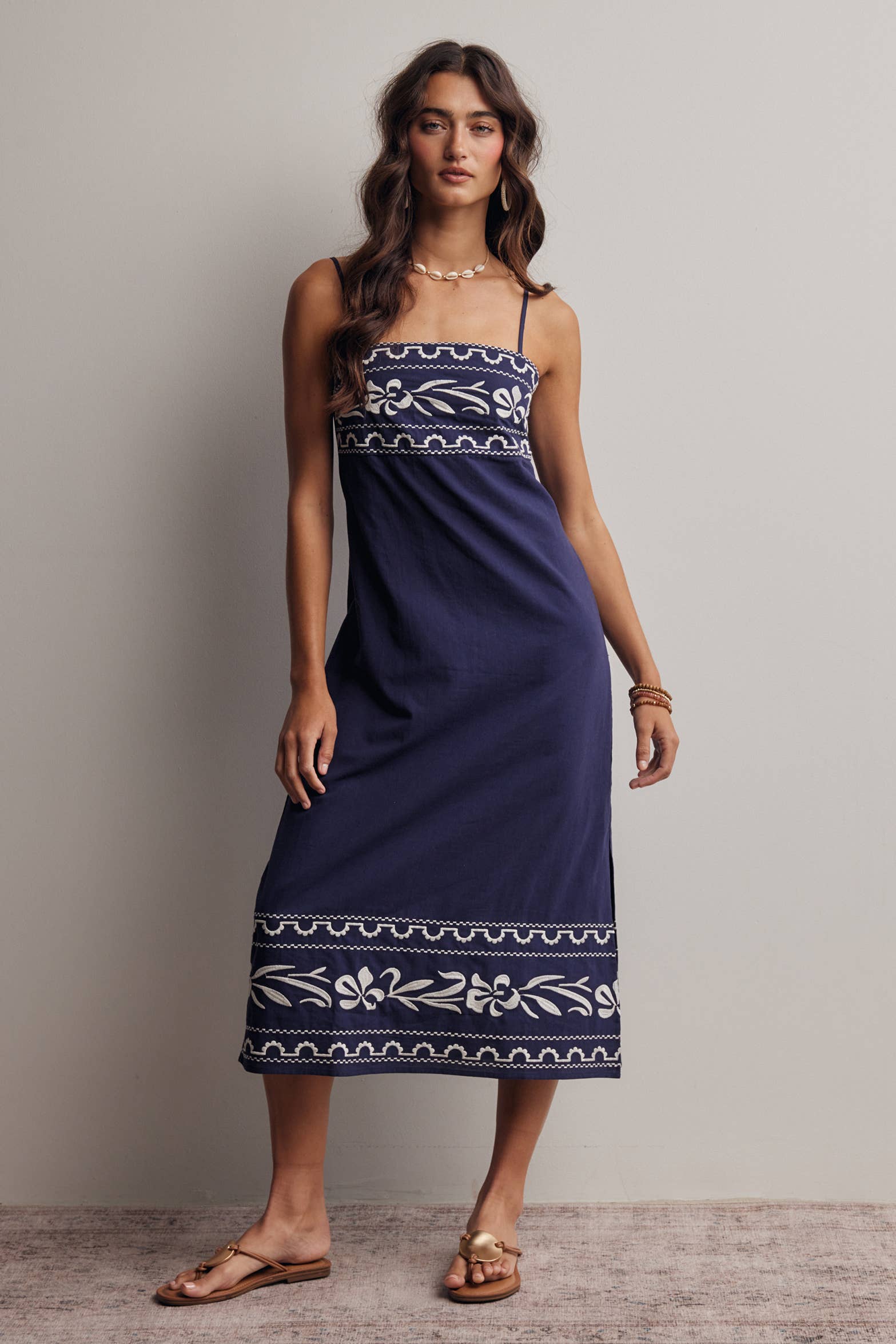 Woman wearing a navy blue dress with white patterns against a plain background