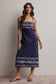 Woman wearing a navy blue dress with white patterns against a plain background