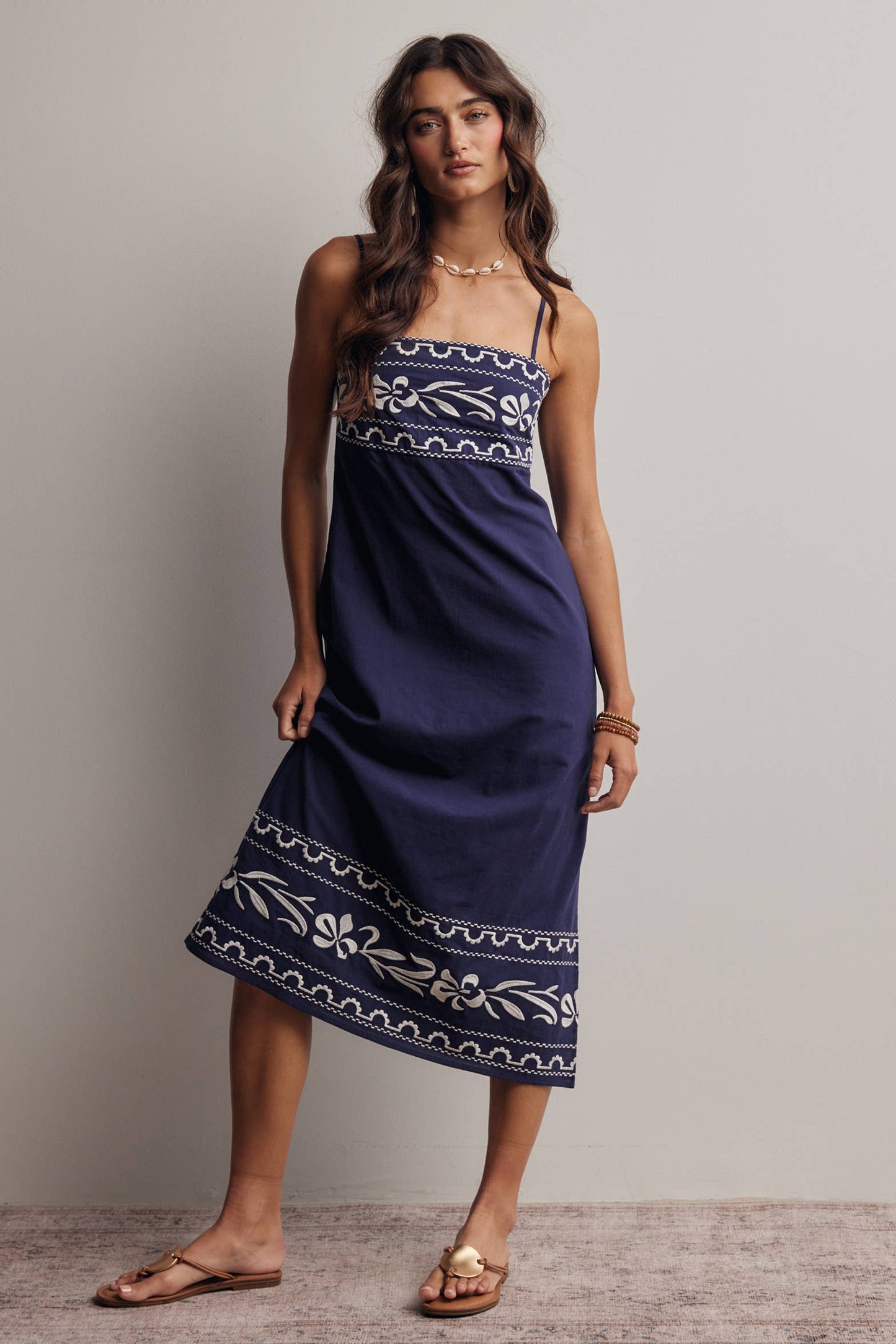 Woman wearing a navy blue dress with white patterns against a plain background