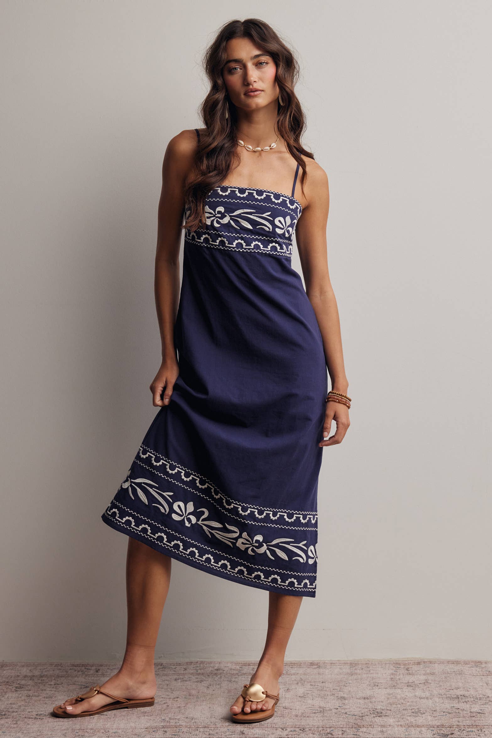 Woman wearing a navy blue dress with white patterns against a plain background