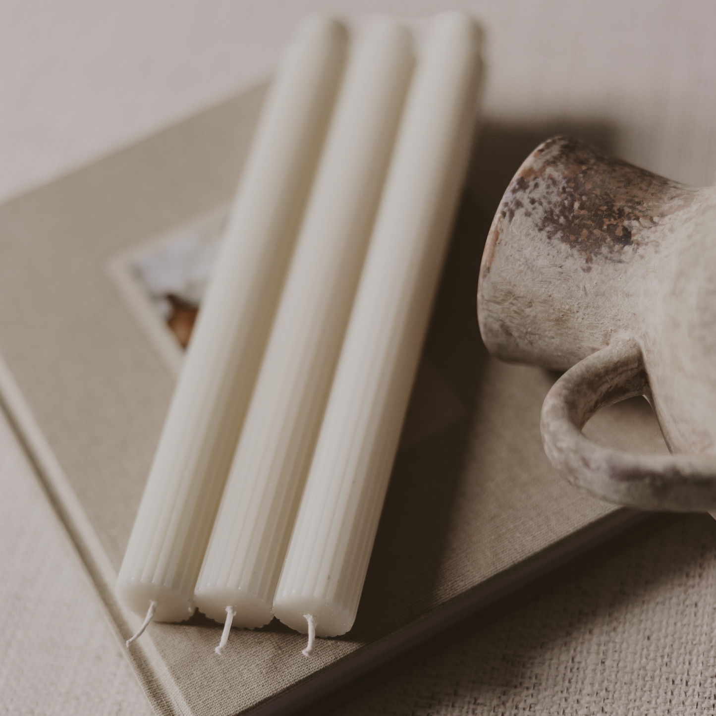 Set of three white fluted taper candles styled with neutral home décor for elegant everyday entertaining.
