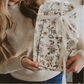 Woman holding a floral-patterned gift box in a kitchen setting