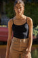 Woman wearing a black tank top and beige pants outdoors