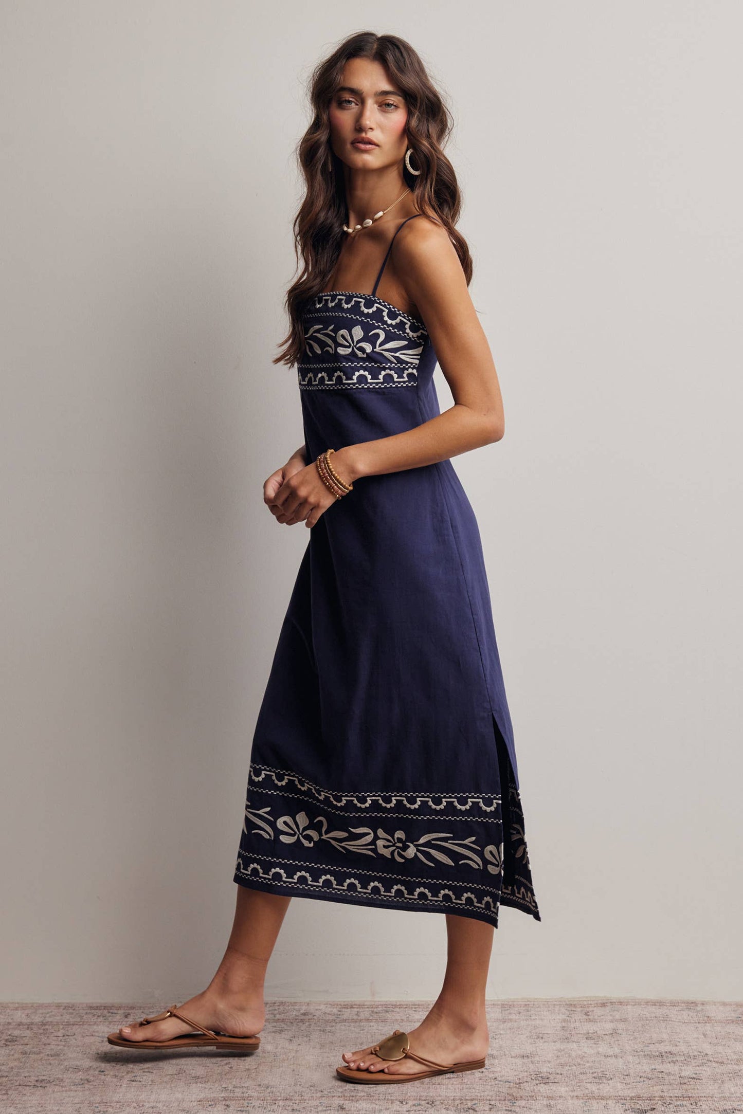 Woman wearing a navy blue dress with white patterns on a plain background