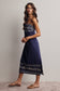 Woman wearing a navy blue dress with white patterns on a plain background