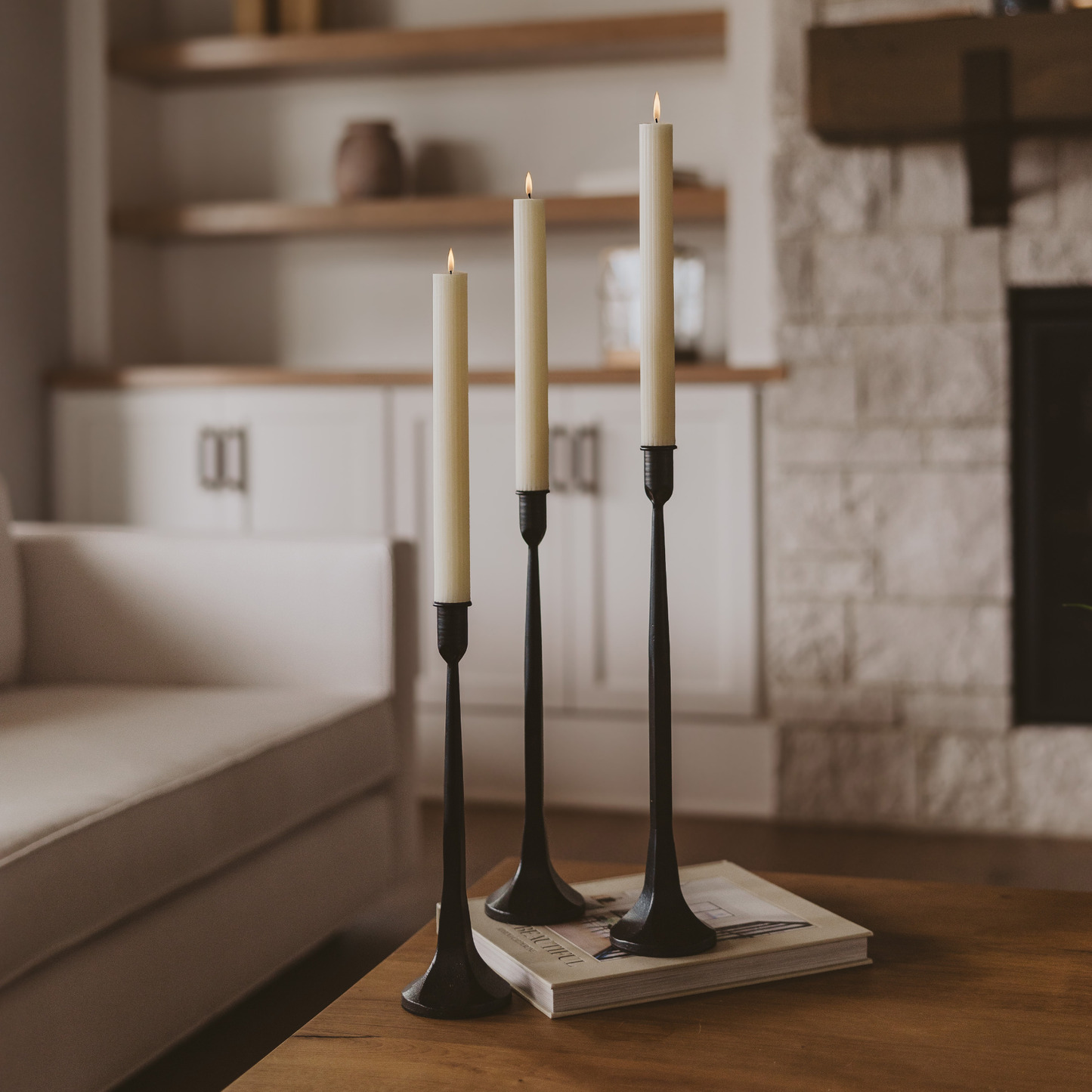 Three candles in black holders on a wooden surface with a blurred background
